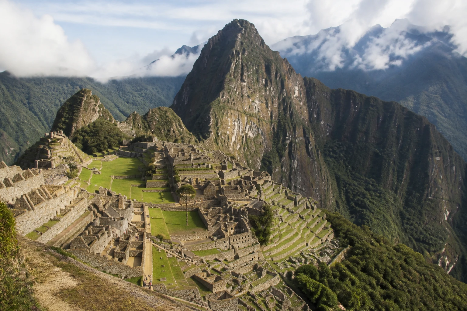 Machu Picchu among green mountain ridges in morning light.
