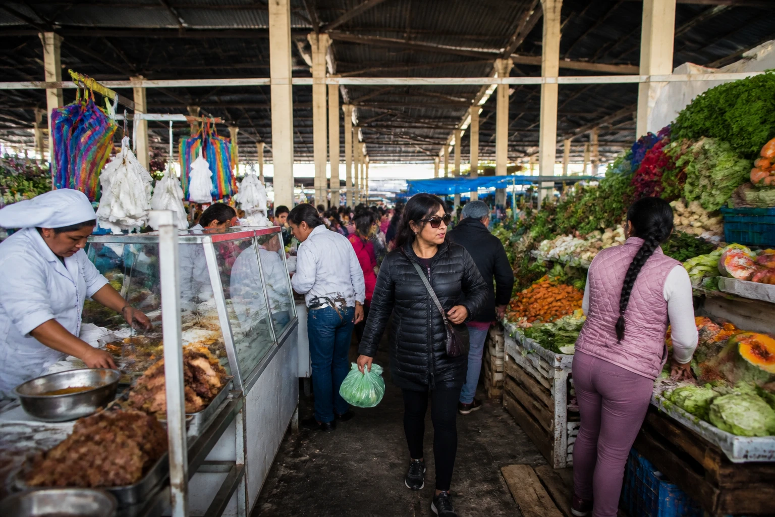 Shoppers moving through a Cusco market aisle