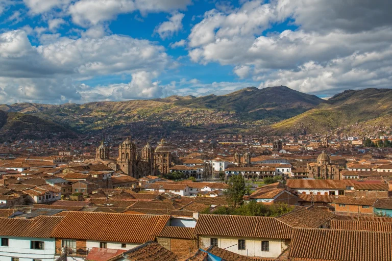 Cusco rooftops and surrounding Andean hills beneath changing clouds