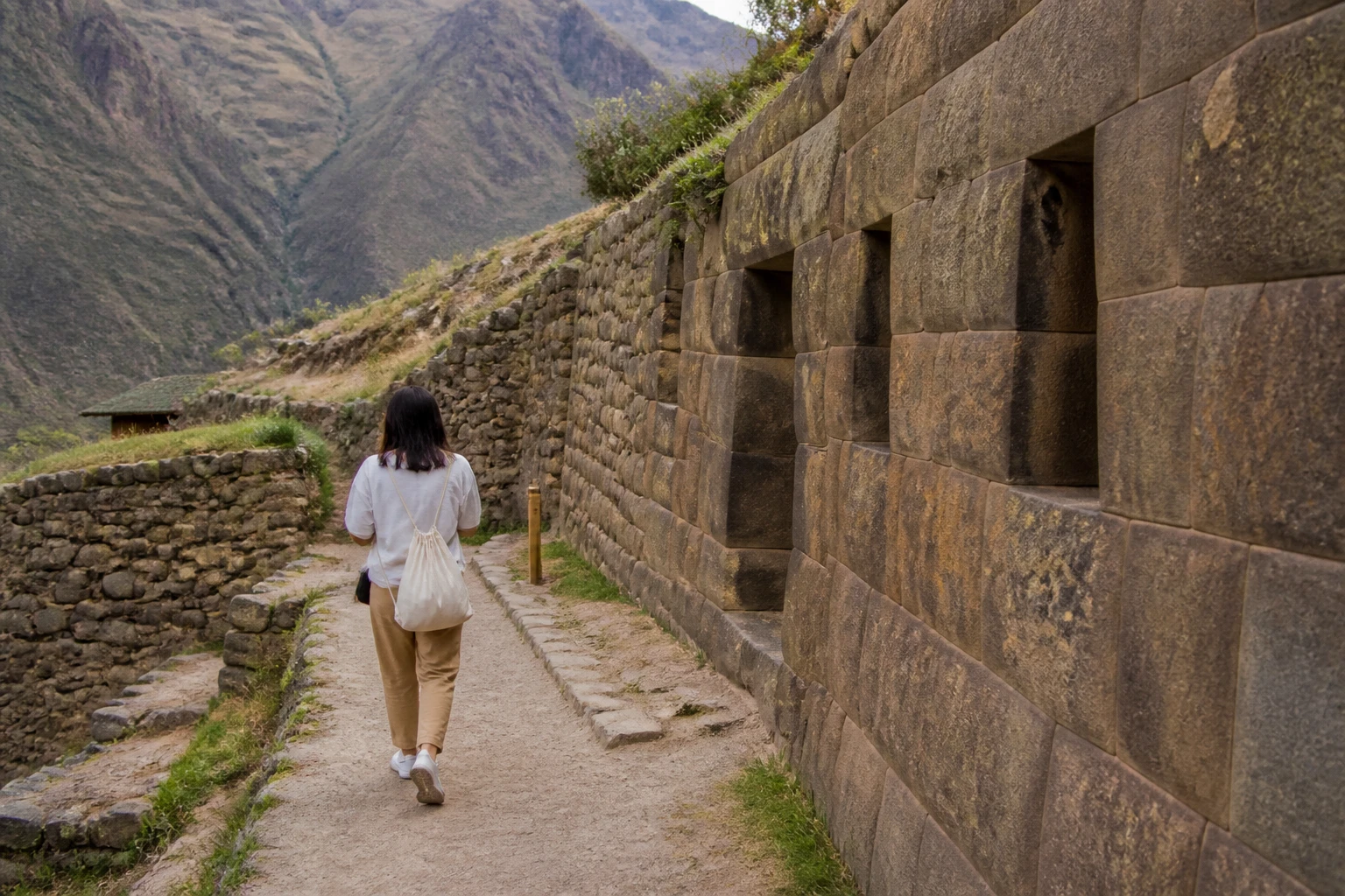 Visitor following a path beside archaeological walls at Pisaq